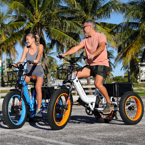 Under the radiant sun amid palm trees, the 3SCORE White fat tire electric trike stands out, combining sleek design with off-road prowess. A man and a woman joyfully traverse the scene, embodying the epitome of carefree exploration on a sunny day with this versatile electric trike.